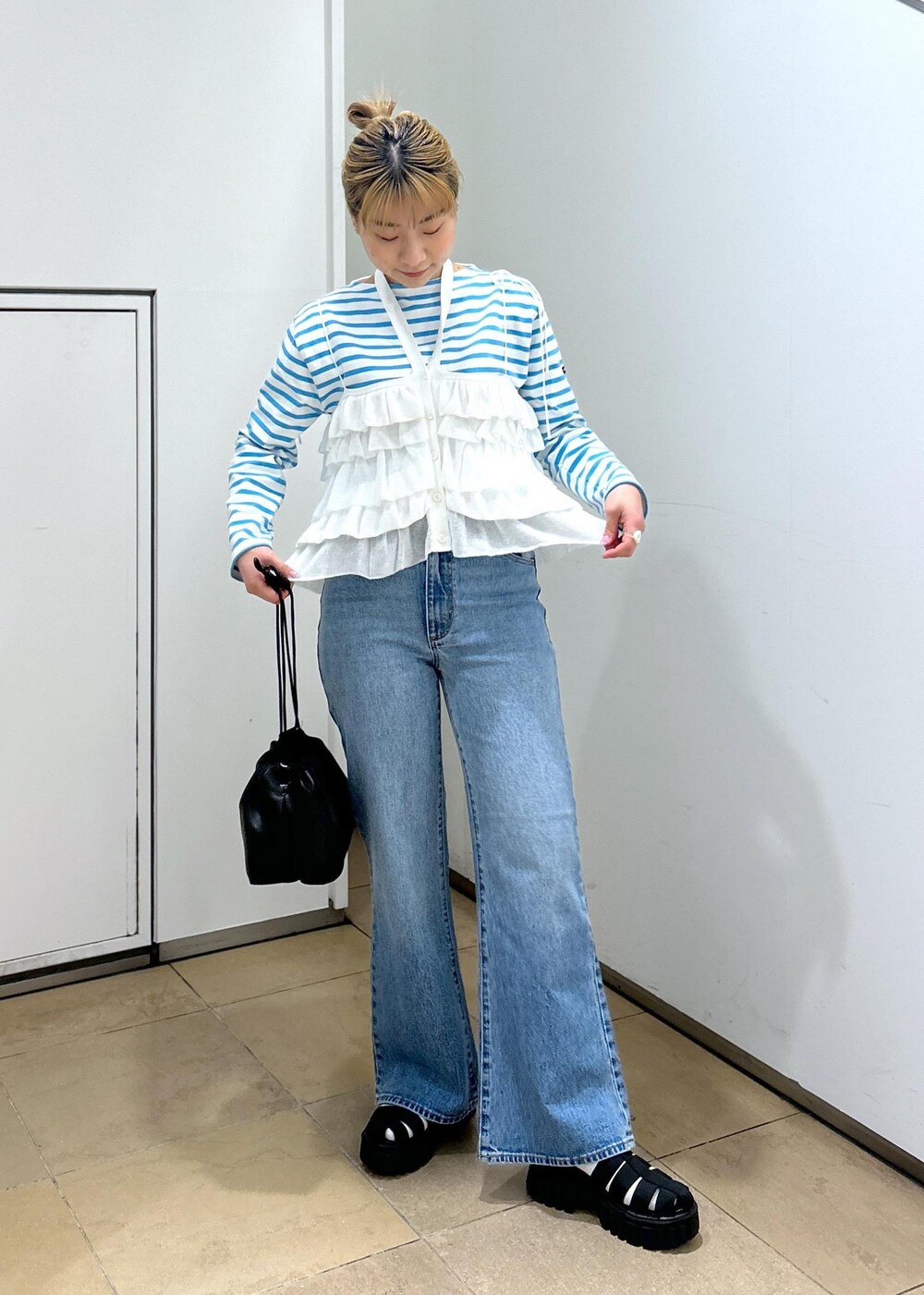 ホワイト系のキャミソール、ブルー系のデニムパンツ、ブラック系のサンダルを着用したレディースの春コーディネートの4枚目の写真