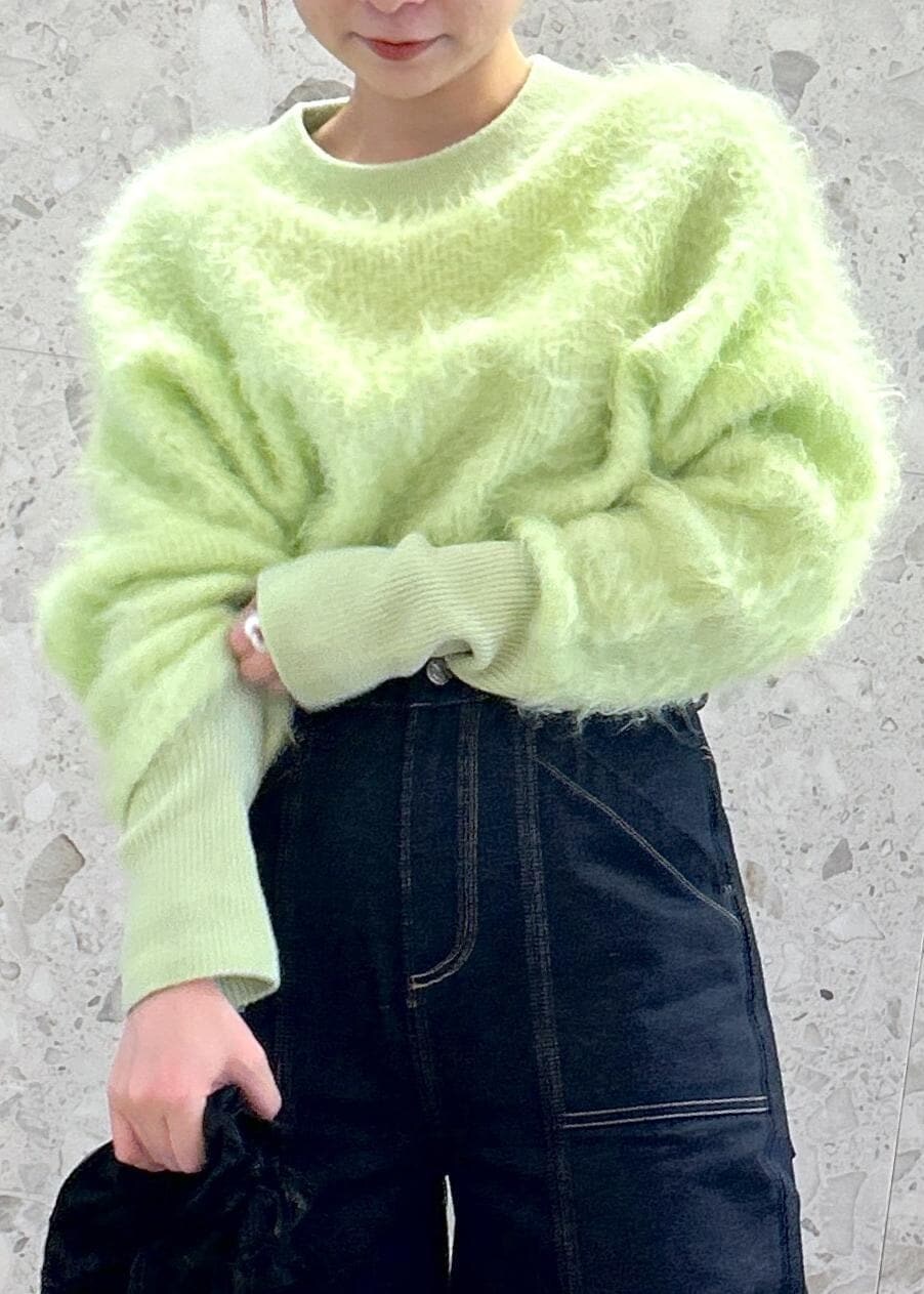 グリーン系のニット/セーター、ブルー系のデニムパンツを着用したレディースの秋コーディネートの5枚目の写真