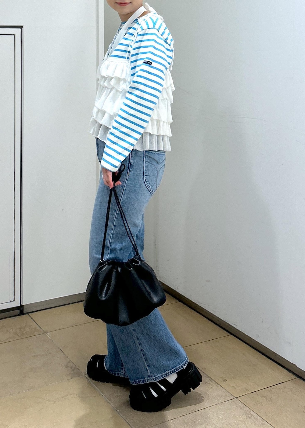 ホワイト系のキャミソール、ブルー系のデニムパンツ、ブラック系のサンダルを着用したレディースの春コーディネートの6枚目の写真