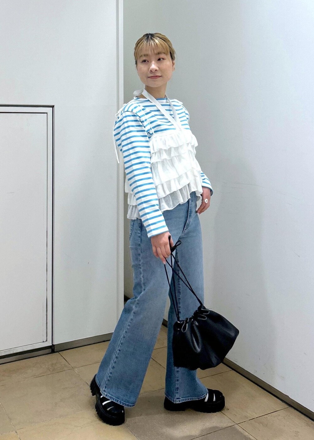 ホワイト系のキャミソール、ブルー系のデニムパンツ、ブラック系のサンダルを着用したレディースの春コーディネートの2枚目の写真