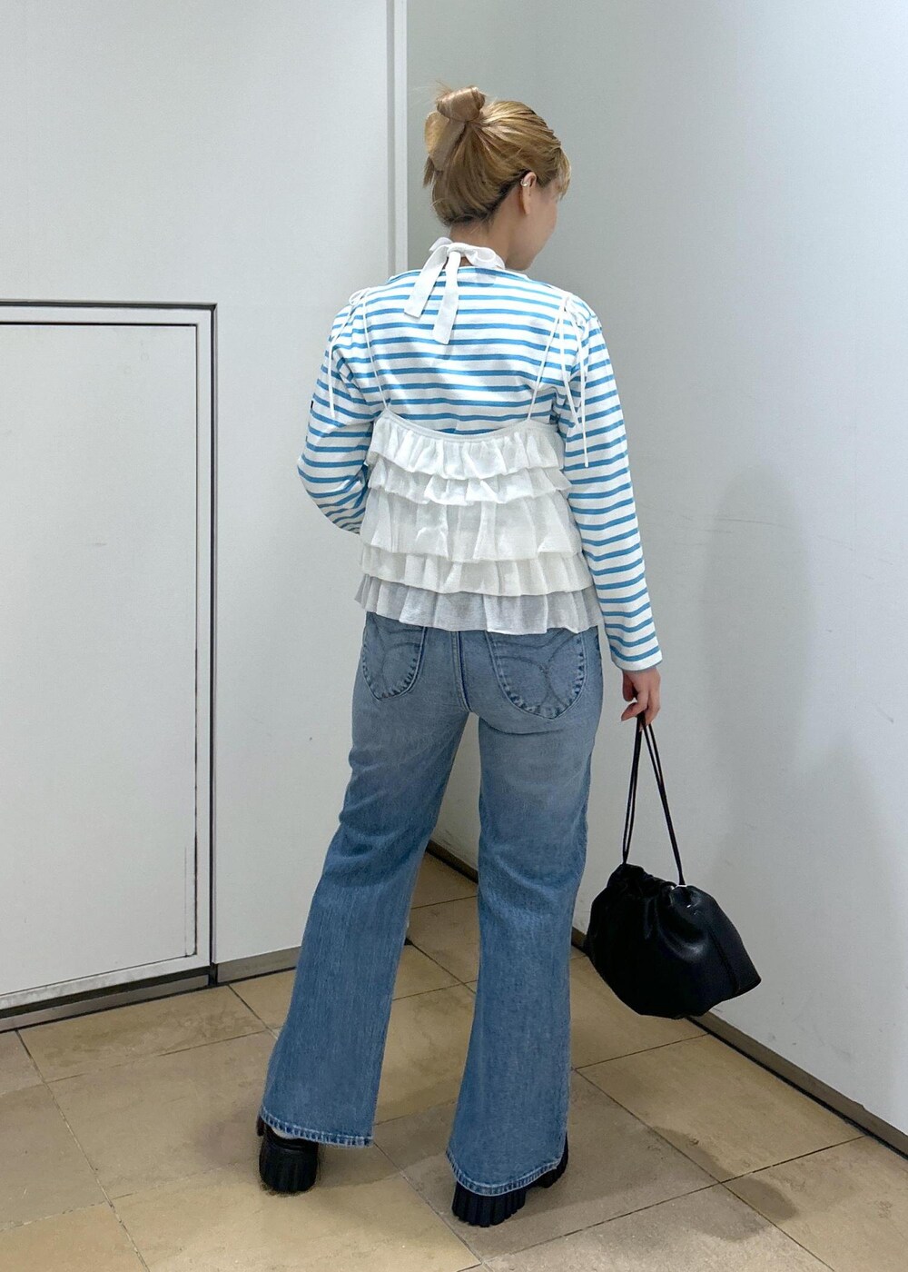 ホワイト系のキャミソール、ブルー系のデニムパンツ、ブラック系のサンダルを着用したレディースの春コーディネートの5枚目の写真