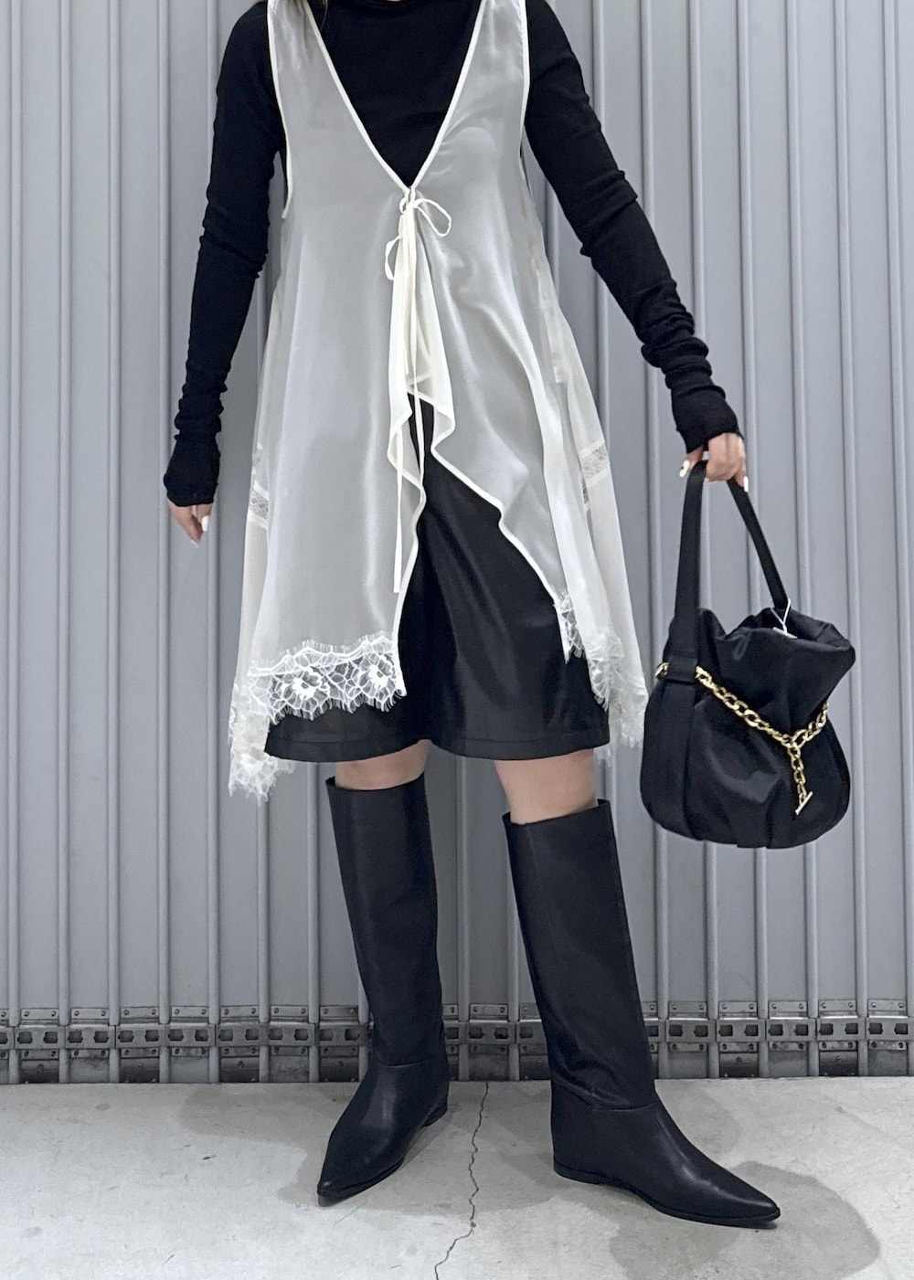 ブラック系のTシャツ/カットソー、ブラック系のブーツ、ブラック系のハンドバッグを着用したレディースの秋コーディネートの7枚目の写真