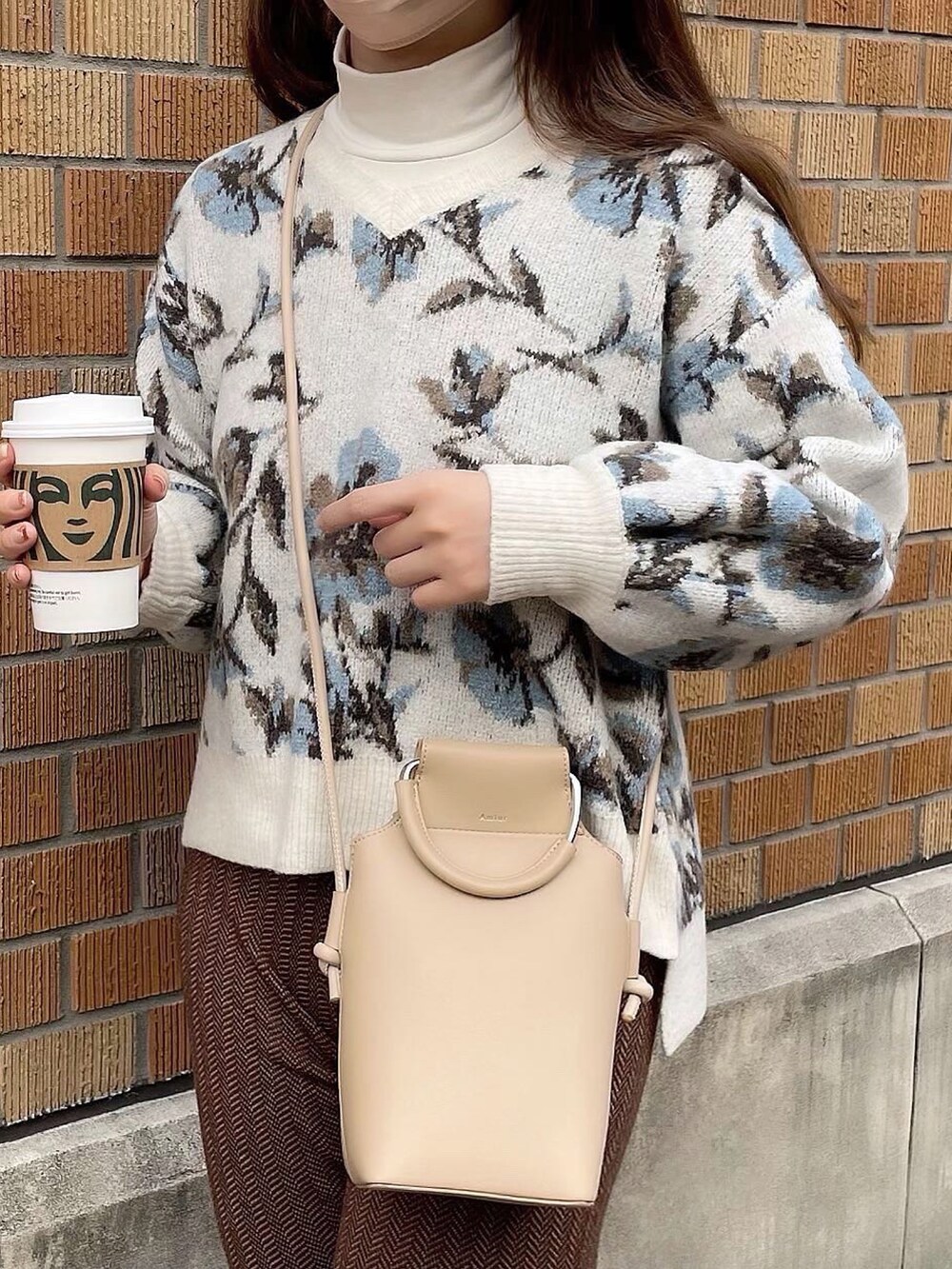 ベージュ系のショルダーバッグ、ブラウン系のその他パンツ、ホワイト系のニット/セーターを着用したレディースの冬コーディネートの3枚目の写真