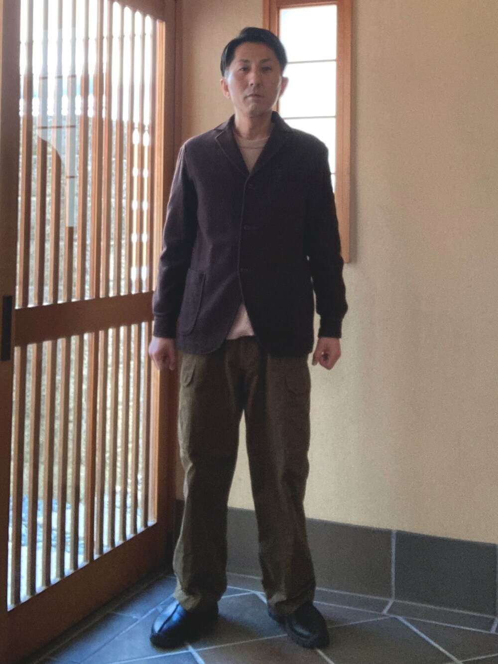 ブラウン系のカーゴパンツ、ブラウン系のジャケット/アウター、ブラック系のスリッポンを着用したメンズの春コーディネートの2枚目の写真