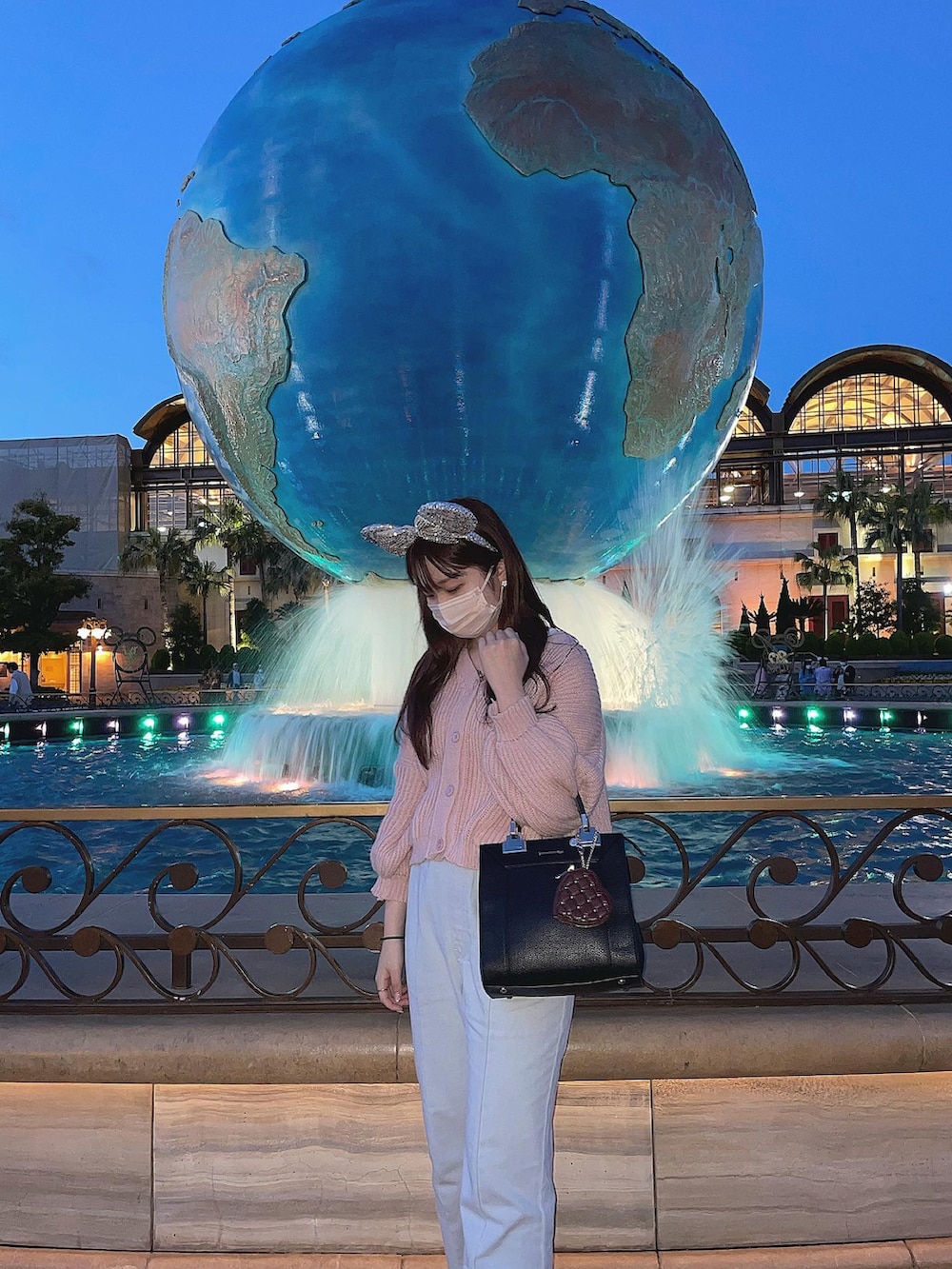 ピンク系のニット/セーター、ブラック系のハンドバッグ、ブルー系のデニムパンツを着用したレディースの春コーディネートの2枚目の写真