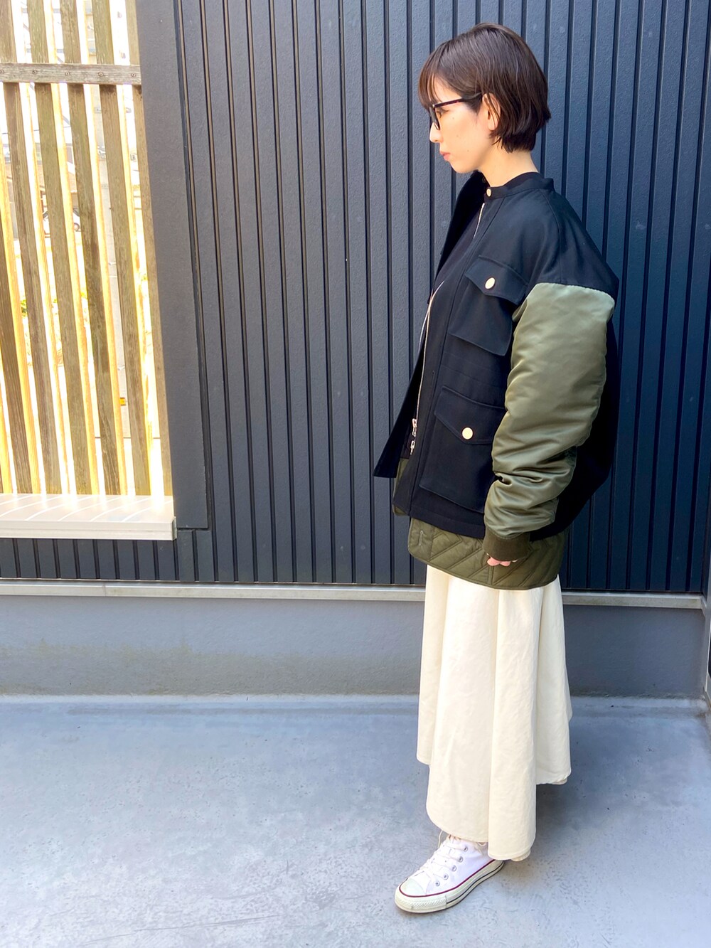 ブラック系のベスト、ホワイト系のスニーカー、ホワイト系のスカートを着用したレディースの冬コーディネートの2枚目の写真