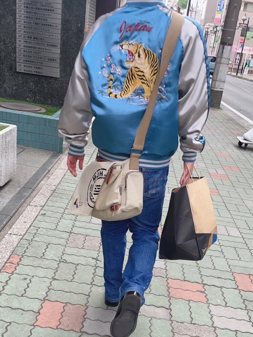 ブルー系のスカジャン、ブルー系のデニムパンツを着用したメンズの春コーディネートの2枚目の写真