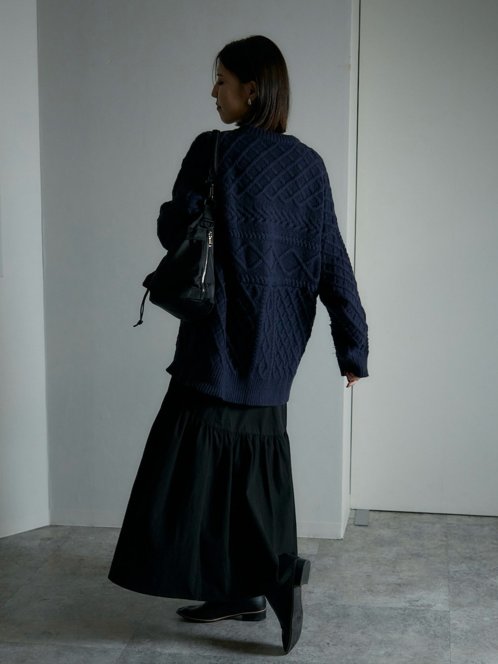 ブラック系のショルダーバッグ、ブルー系のニット/セーター、ブラック系のブーツを着用したレディースの秋コーディネートの2枚目の写真