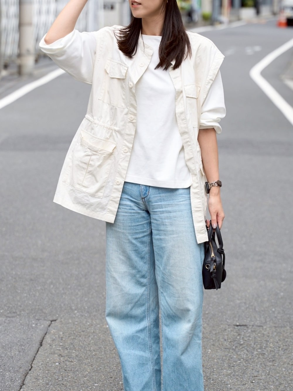 ホワイト系のTシャツ/カットソー、ホワイト系のベスト、ブルー系のデニムパンツを着用したレディースの秋コーディネートの4枚目の写真