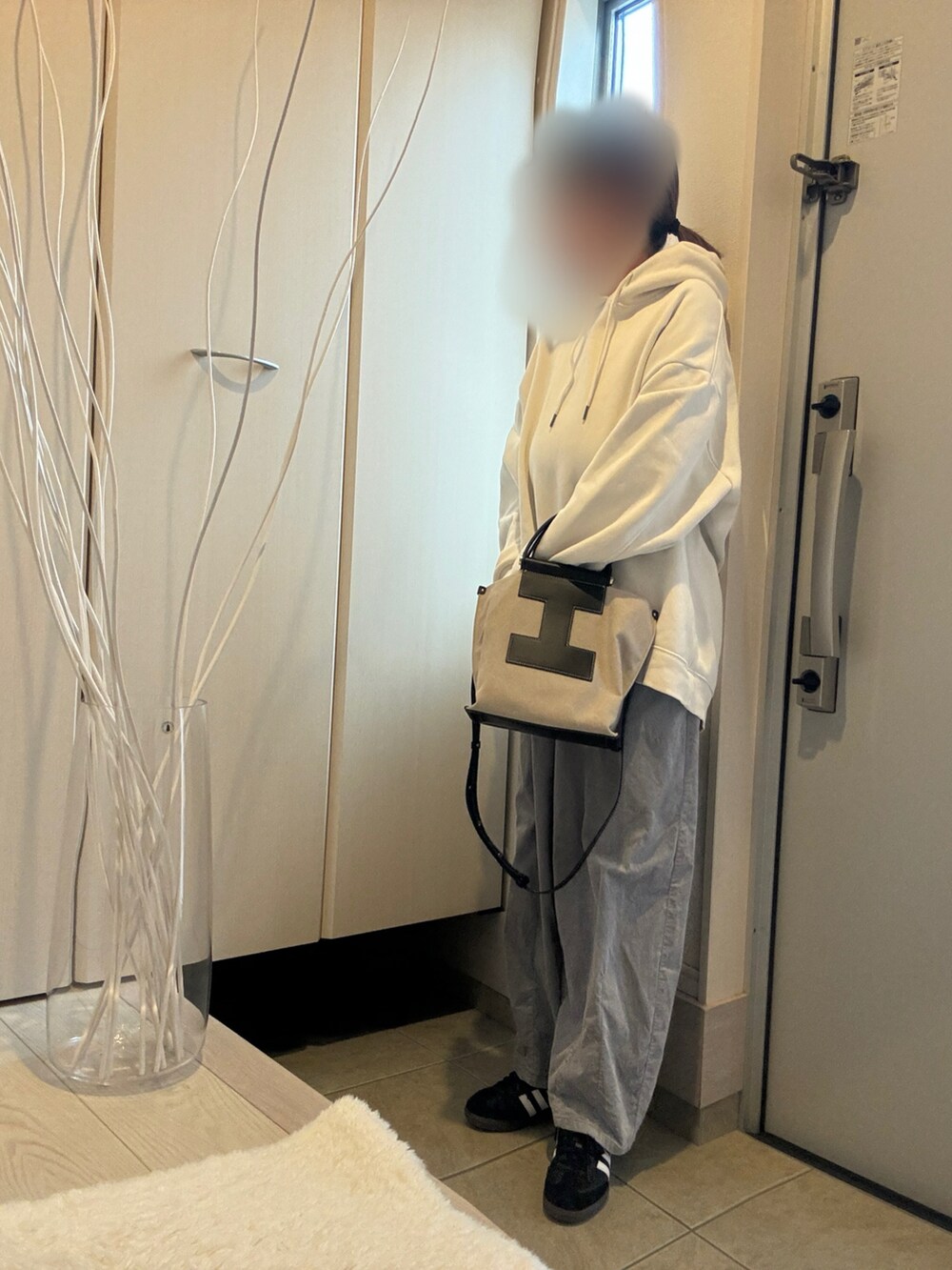 ブラック系のトートバッグ、ホワイト系のパーカー、ブラック系のスニーカーを着用したレディースの冬コーディネートの2枚目の写真