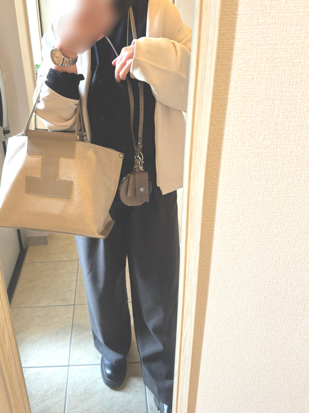 ベージュ系のバッグ、ブラック系のニット/セーター、ゴールド系の腕時計を着用したレディースの冬コーディネートの2枚目の写真