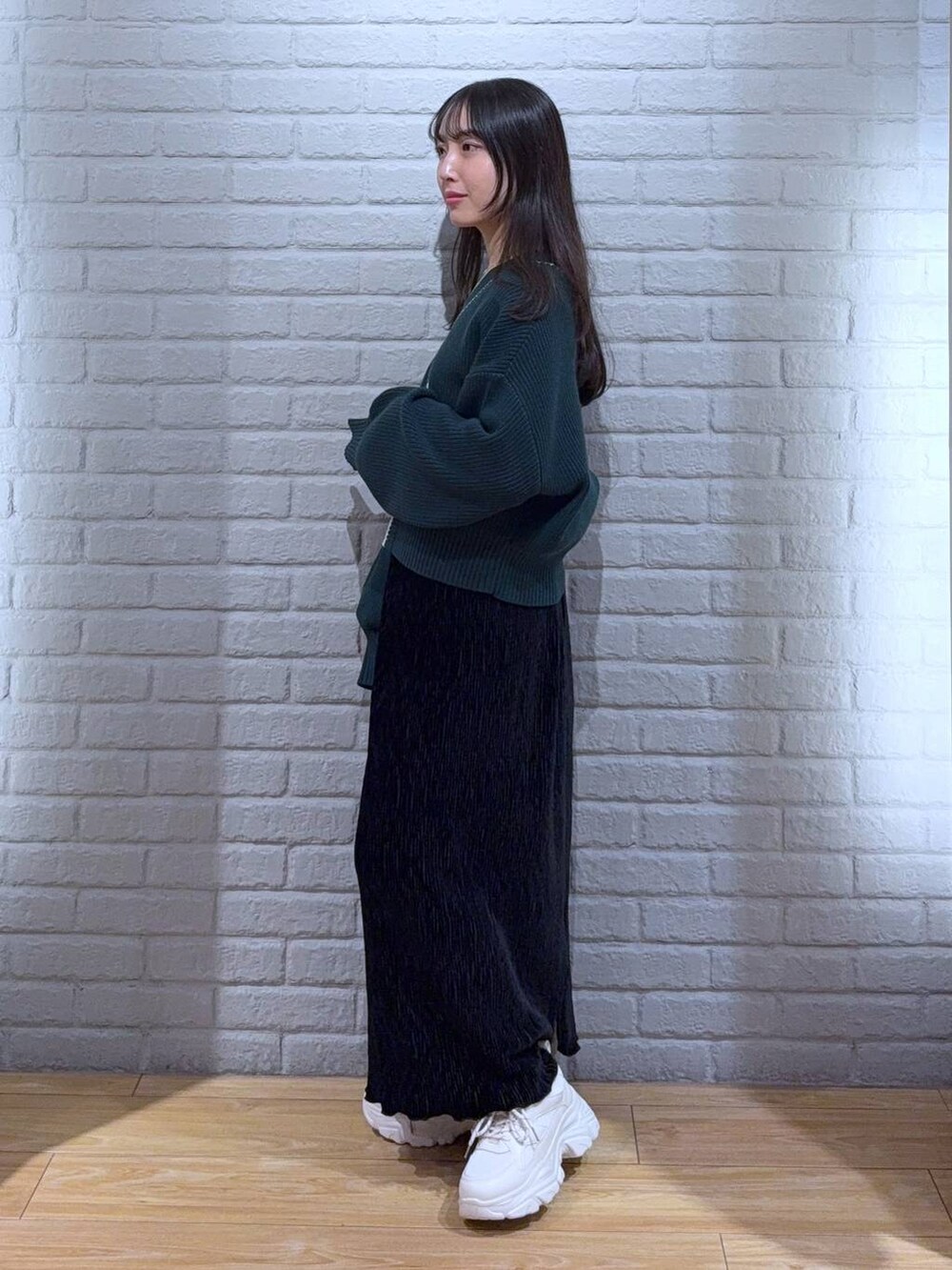 シルバー系のタンクトップ、グリーン系のカーディガン/ボレロ、ホワイト系のスニーカーを着用したレディースの秋コーディネートの3枚目の写真