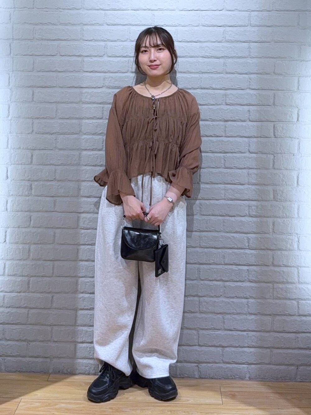 ブラック系のショルダーバッグ、ブラウン系のシャツ/ブラウス、グレー系のスウェットパンツを着用したレディースの春コーディネートの2枚目の写真