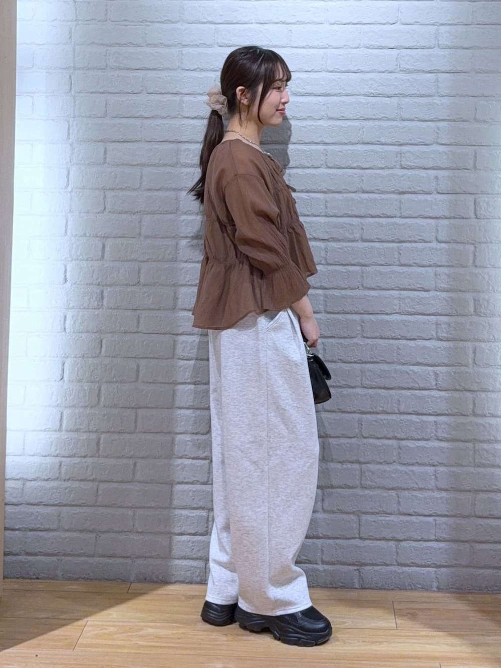 ブラック系のショルダーバッグ、ブラウン系のシャツ/ブラウス、グレー系のスウェットパンツを着用したレディースの春コーディネートの3枚目の写真