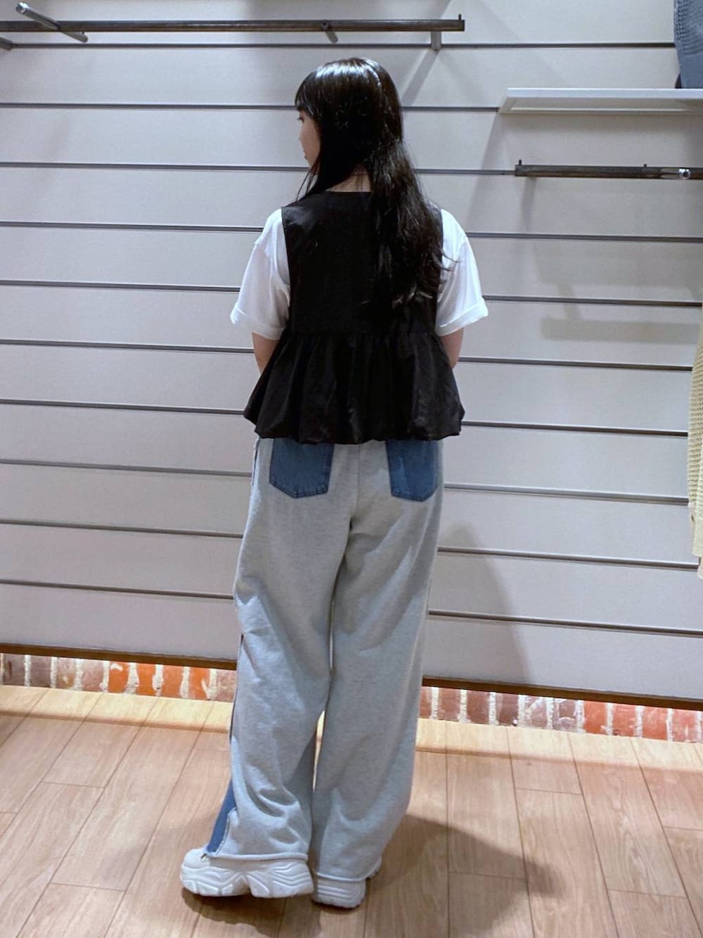 ブルー系のデニムパンツ、ブラック系のベスト、シルバー系のショルダーバッグを着用したレディースの夏コーディネートの5枚目の写真