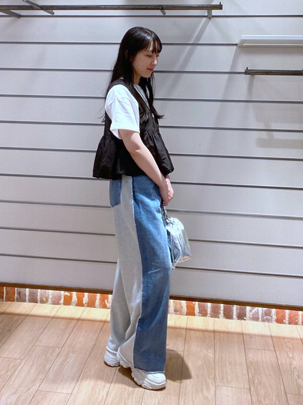 ブルー系のデニムパンツ、ブラック系のベスト、シルバー系のショルダーバッグを着用したレディースの夏コーディネートの4枚目の写真