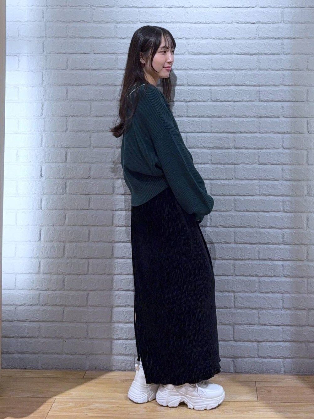 シルバー系のタンクトップ、グリーン系のカーディガン/ボレロ、ホワイト系のスニーカーを着用したレディースの秋コーディネートの2枚目の写真