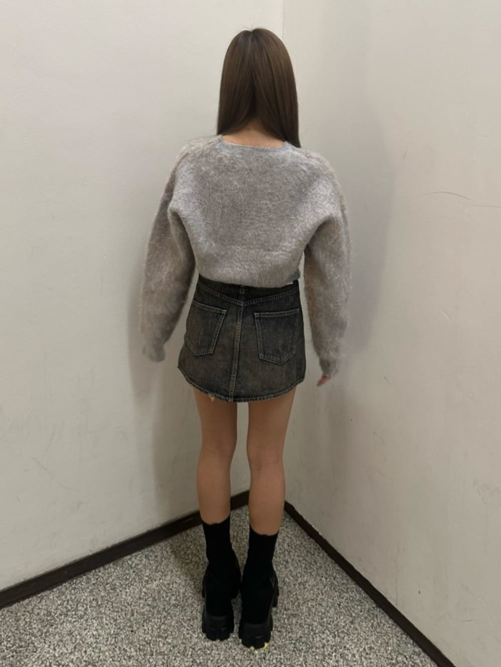 グレー系のニット/セーター、ブルー系のデニムスカート、ブラック系のブーツを着用したレディースの冬コーディネートの3枚目の写真