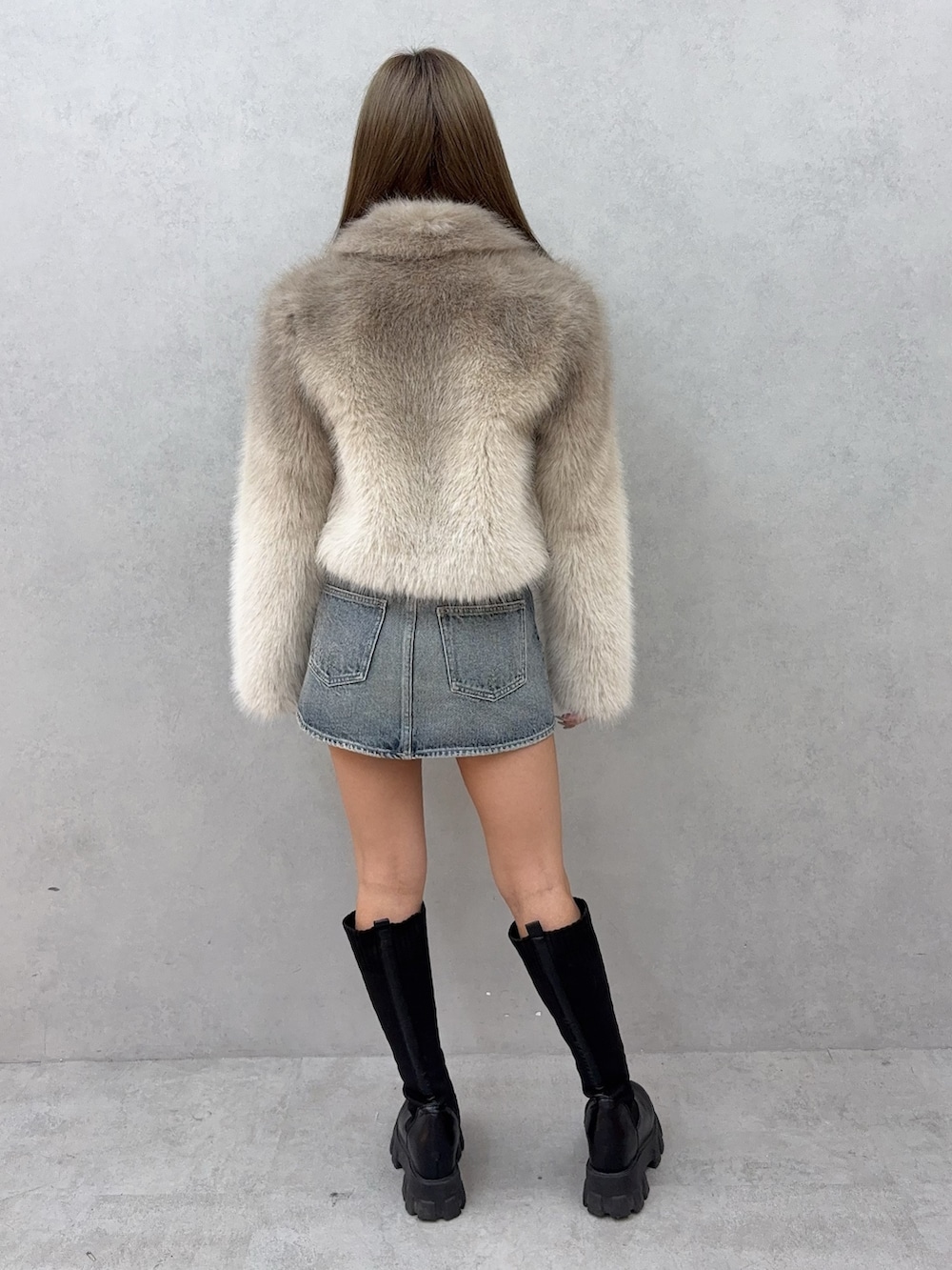 ホワイト系のニット/セーター、ブルー系のデニムスカート、ブラック系のブーツを着用したレディースの秋コーディネートの3枚目の写真