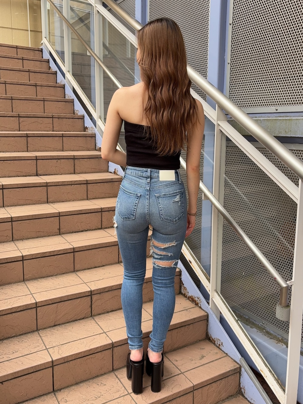 ブラック系のニット/セーター、ブルー系のデニムパンツ、ブラック系のサンダルを着用したレディースの夏コーディネートの3枚目の写真