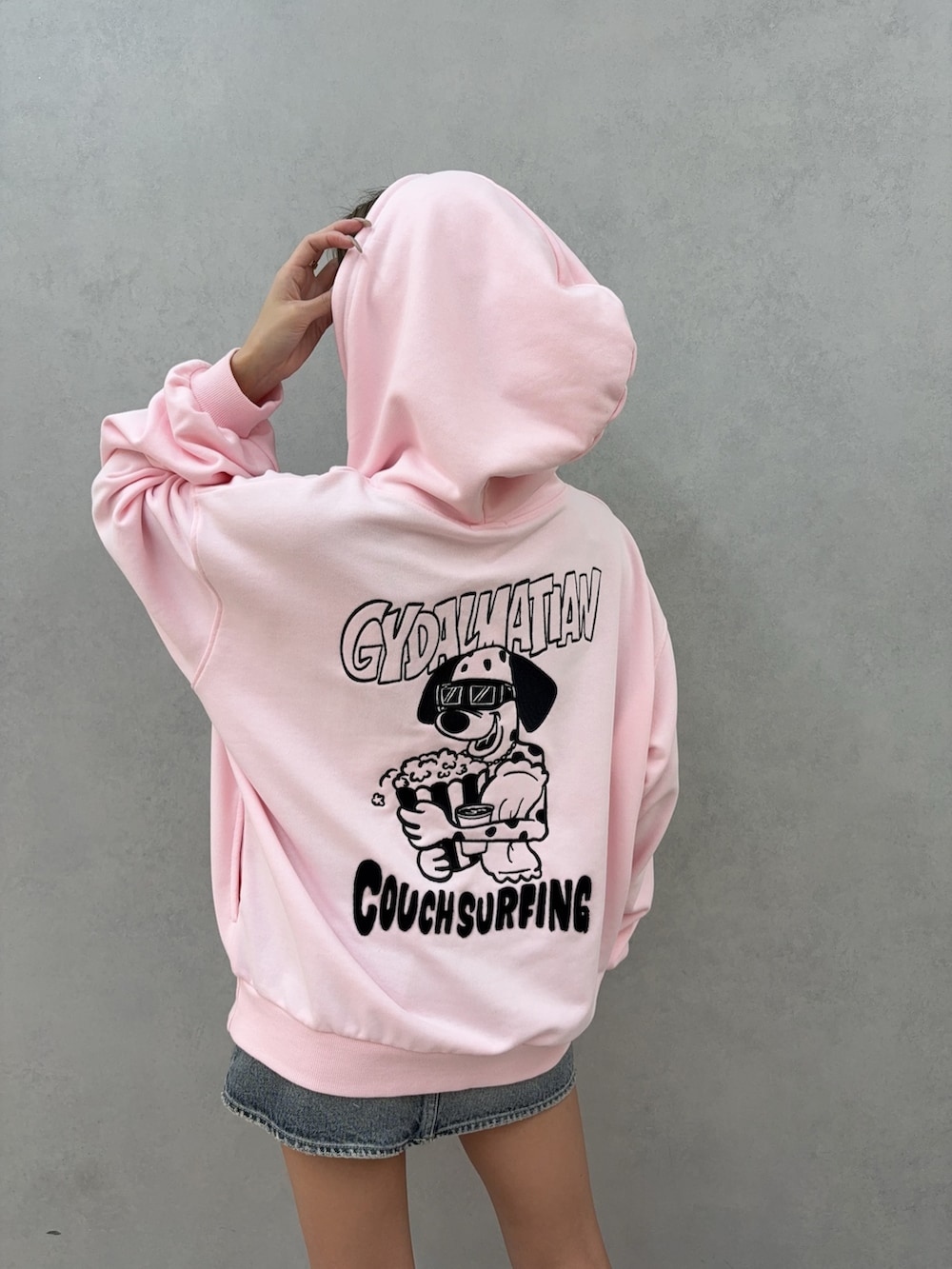 ピンク系のパーカー、ブルー系のデニムスカート、ベージュ系のブーツを着用したレディースの秋コーディネートの4枚目の写真