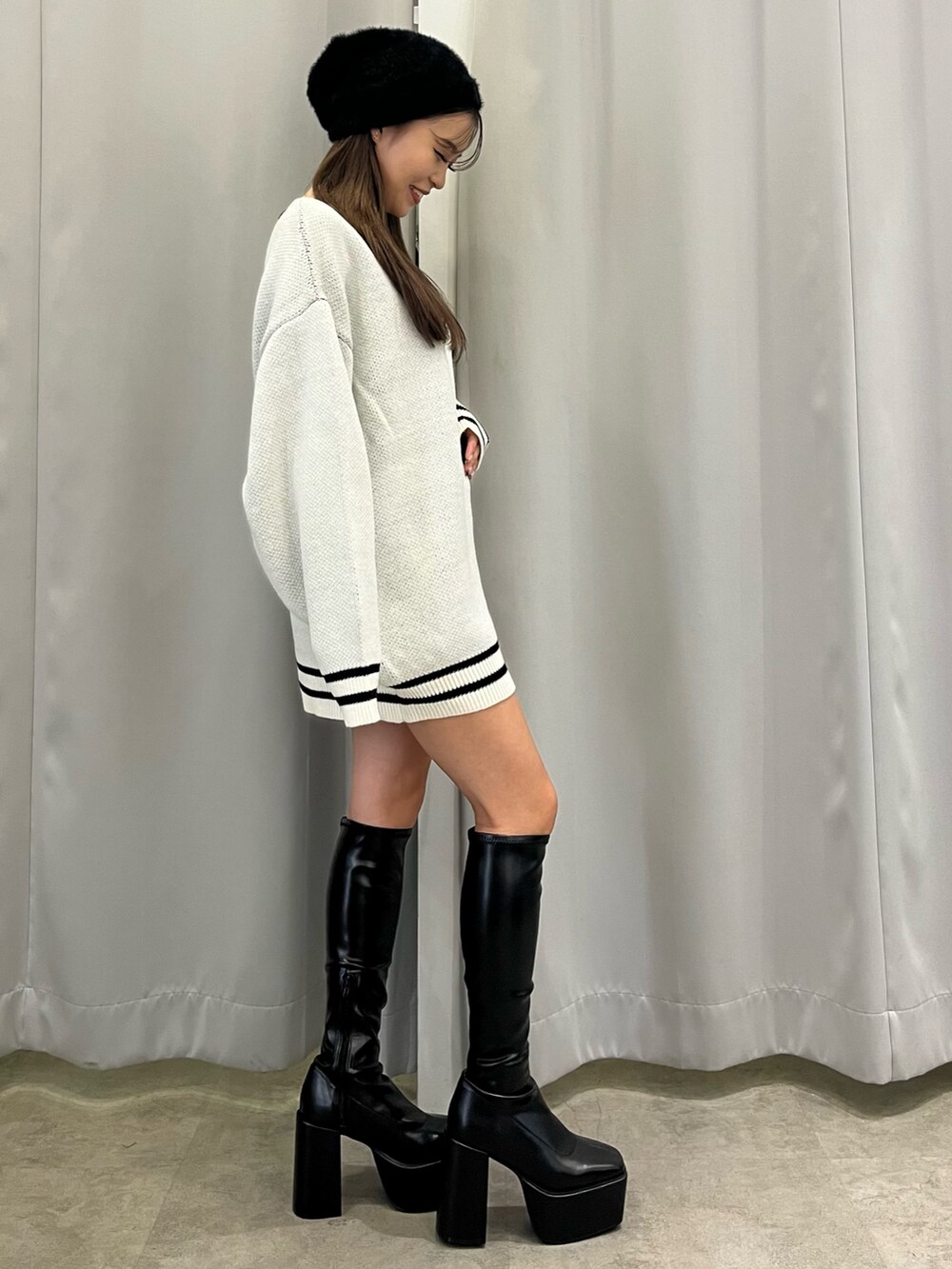 ホワイト系のニット/セーター、ブラック系のブーツ、ブラック系のニットキャップ/ビーニーを着用したレディースの秋コーディネートの2枚目の写真