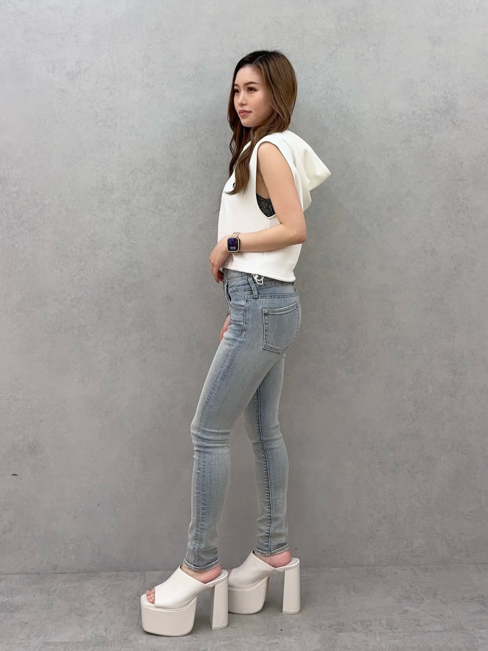 ホワイト系のパーカー、ブルー系のデニムパンツ、ホワイト系のサンダルを着用したレディースの夏コーディネートの2枚目の写真