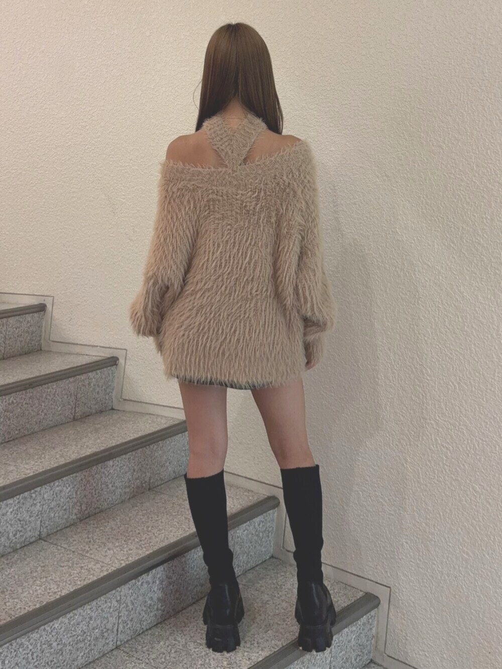 ブルー系のデニムスカート、ブラック系のブーツ、ベージュ系のニット/セーターを着用したレディースの秋コーディネートの4枚目の写真