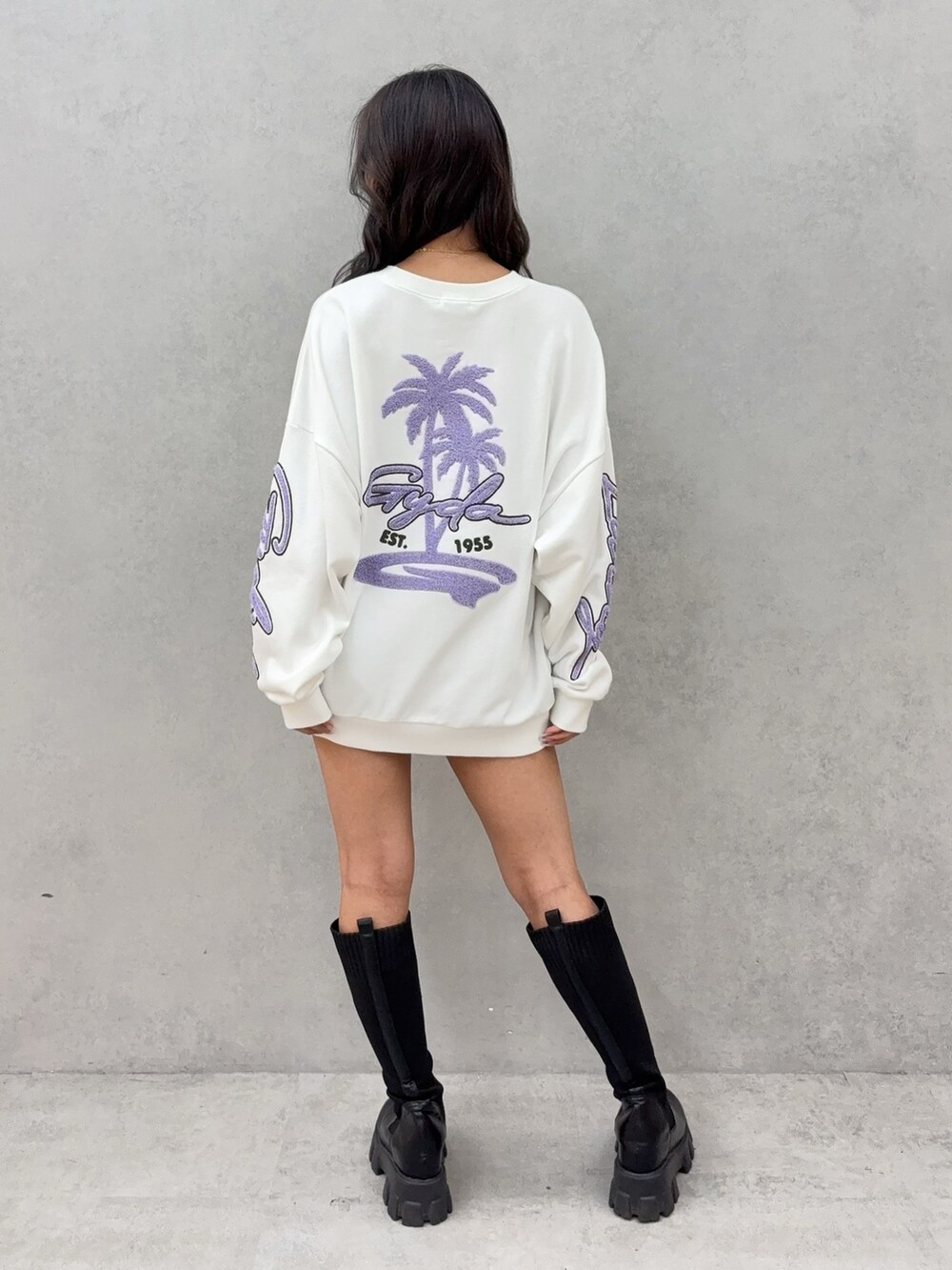 ホワイト系のスウェット、ブルー系のデニムスカート、ブラック系のブーツを着用したレディースの秋コーディネートの3枚目の写真