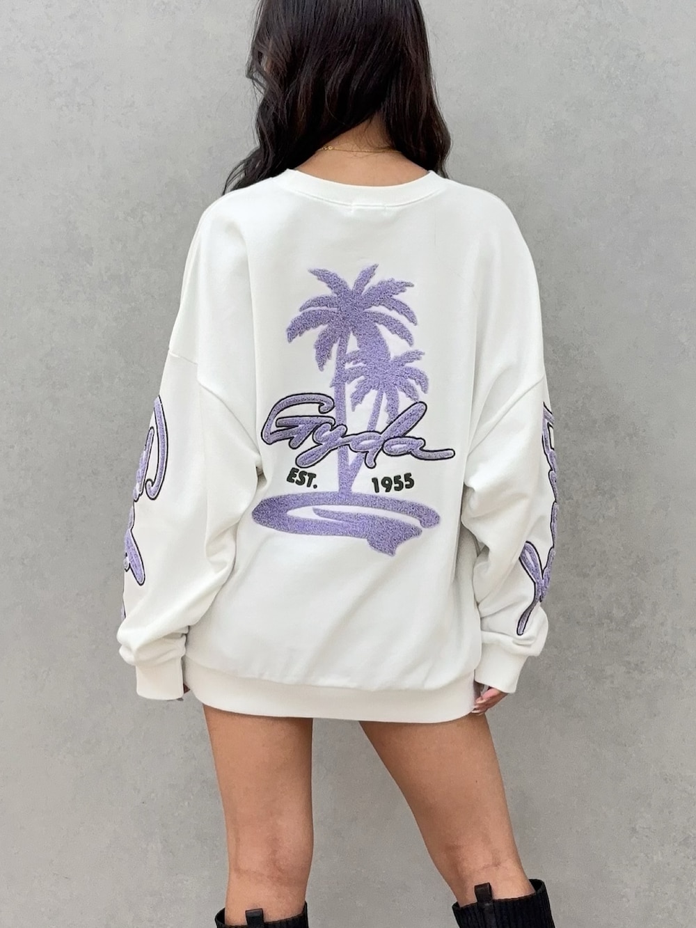 ホワイト系のスウェット、ブルー系のデニムスカート、ブラック系のブーツを着用したレディースの秋コーディネートの4枚目の写真