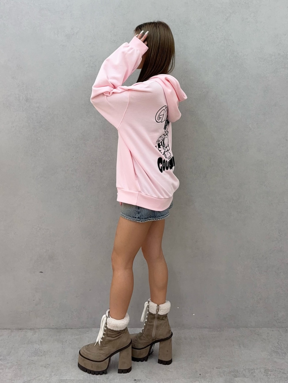 ピンク系のパーカー、ブルー系のデニムスカート、ベージュ系のブーツを着用したレディースの秋コーディネートの2枚目の写真