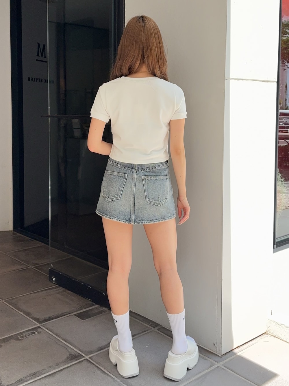 ホワイト系のTシャツ/カットソー、ブルー系のデニムスカート、ホワイト系のサンダルを着用したレディースの夏コーディネートの3枚目の写真