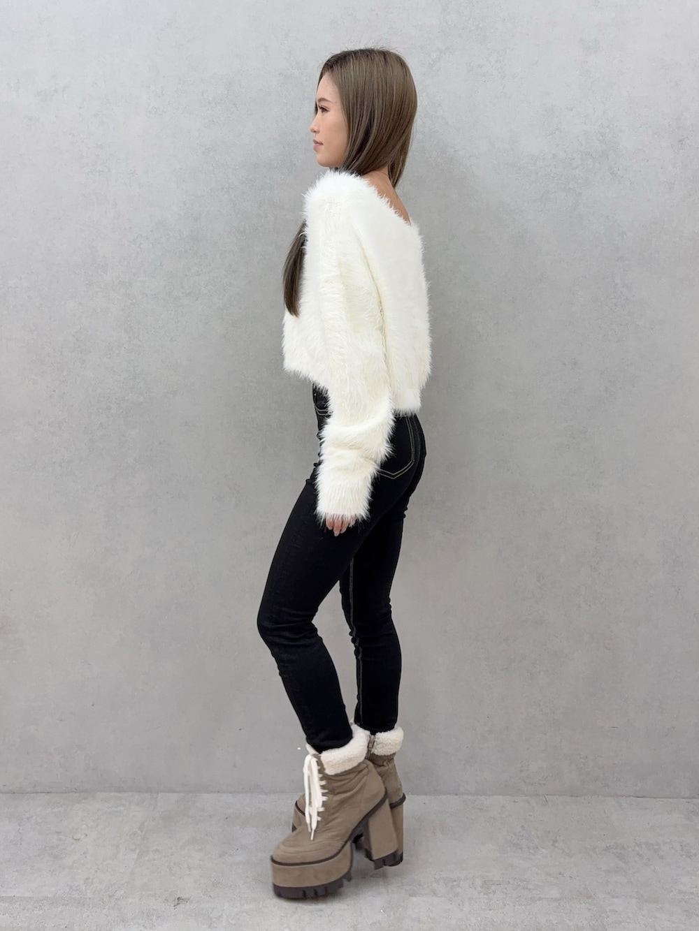 ブラック系のデニムパンツ、ベージュ系のブーツ、ホワイト系のニット/セーターを着用したレディースの秋コーディネートの2枚目の写真