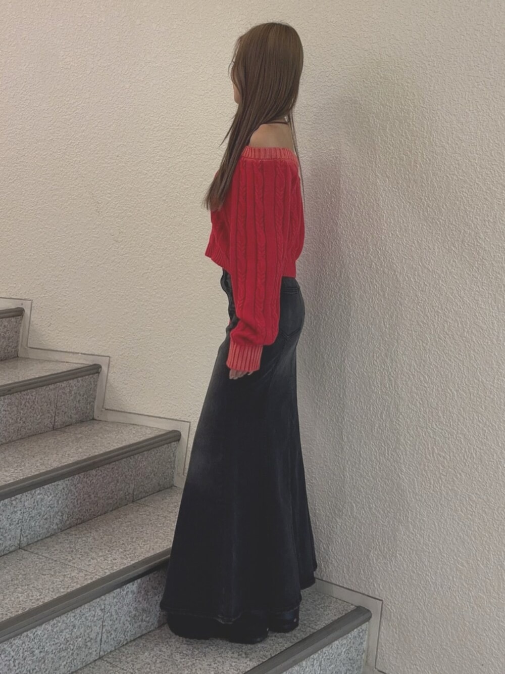 ブラック系のブーツ、レッド系のニット/セーター、ブラック系のデニムスカートを着用したレディースの秋コーディネートの2枚目の写真