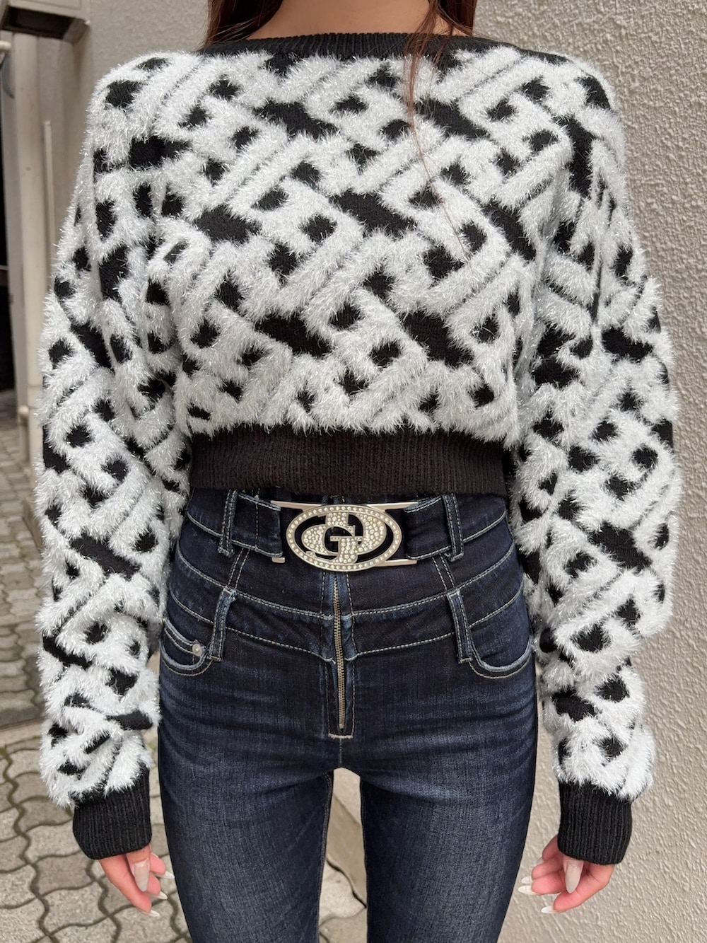 ブラック系のニット/セーター、ブルー系のデニムパンツ、ブラック系のブーツを着用したレディースの秋コーディネートの4枚目の写真