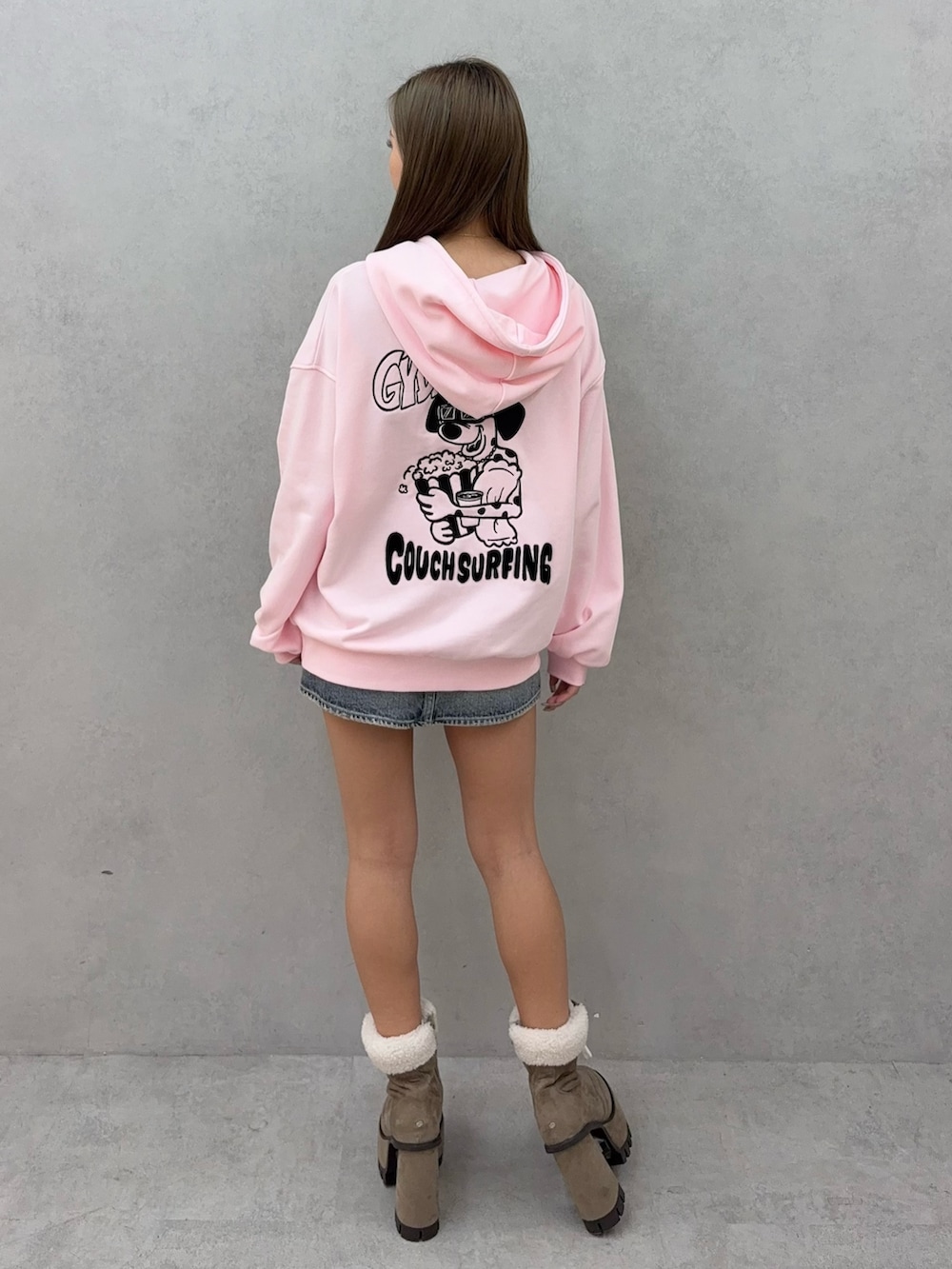 ピンク系のパーカー、ブルー系のデニムスカート、ベージュ系のブーツを着用したレディースの秋コーディネートの3枚目の写真