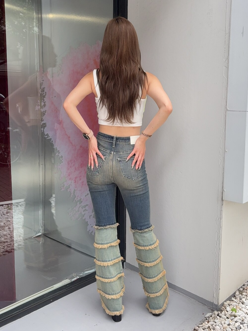 ブルー系のデニムパンツ、ブラック系のサンダル、ホワイト系のキャミソールを着用したレディースの夏コーディネートの3枚目の写真