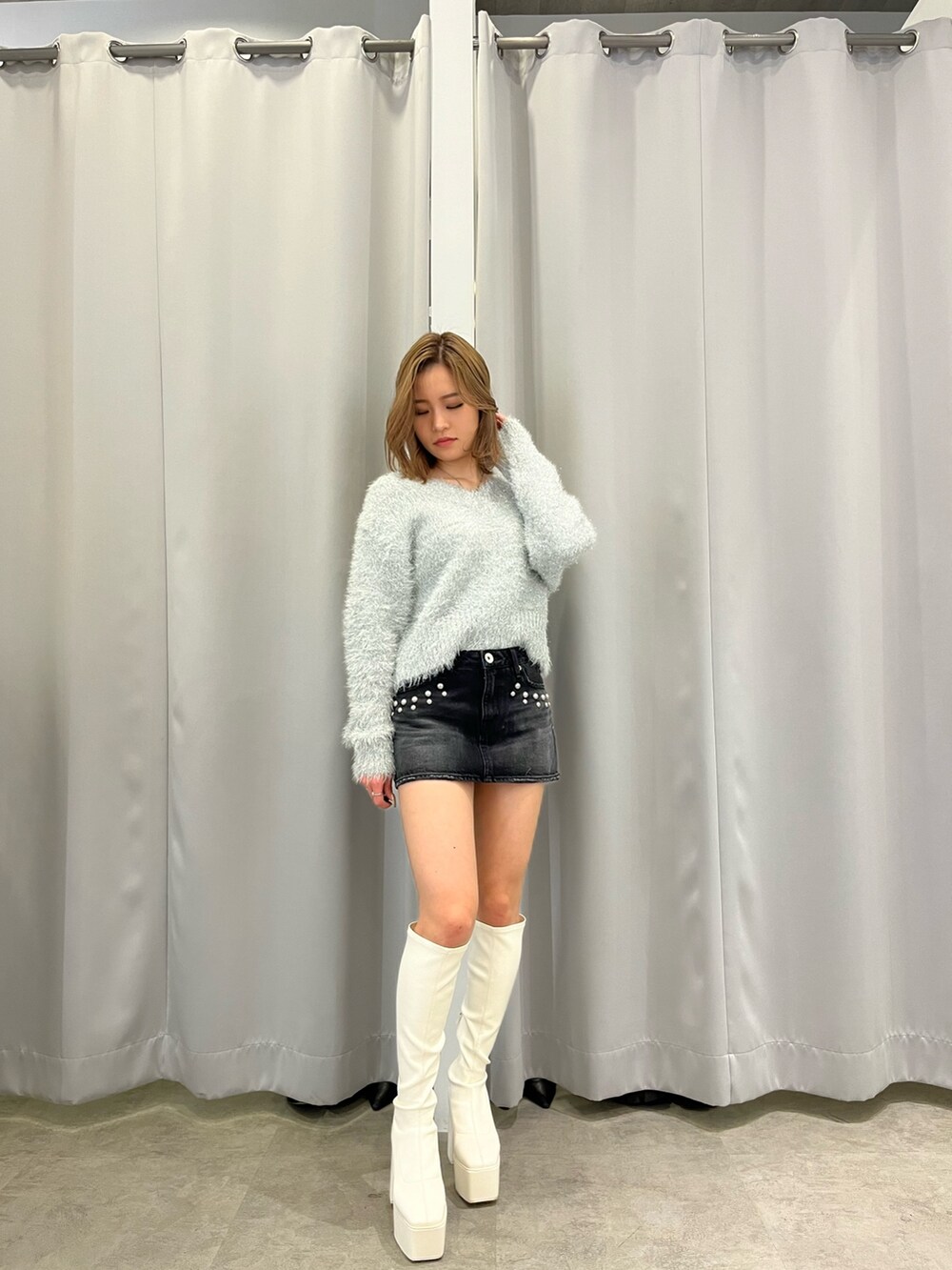 ホワイト系のダウンジャケット/コート、グレー系のニット/セーター、ブラック系のデニムスカートを着用したレディースの冬コーディネートの2枚目の写真