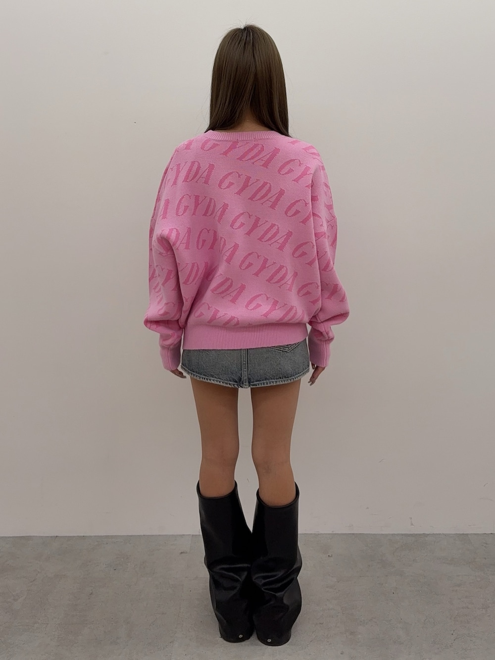 ピンク系のニット/セーター、ブルー系のデニムスカート、ブラック系のブーツを着用したレディースの秋コーディネートの3枚目の写真