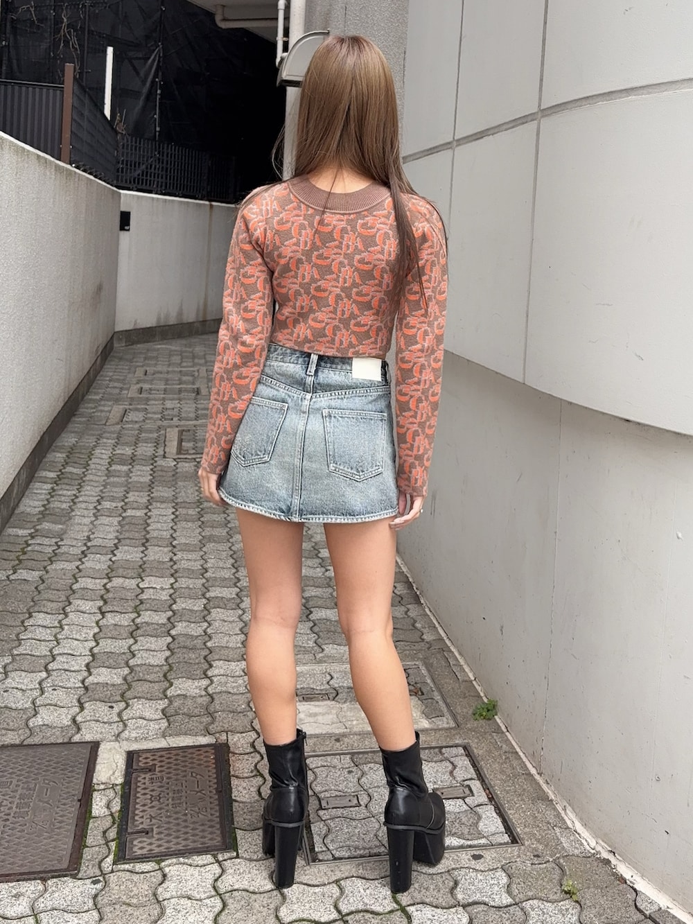オレンジ系のニット/セーター、ブルー系のデニムスカート、ブラック系のブーツを着用したレディースの秋コーディネートの3枚目の写真