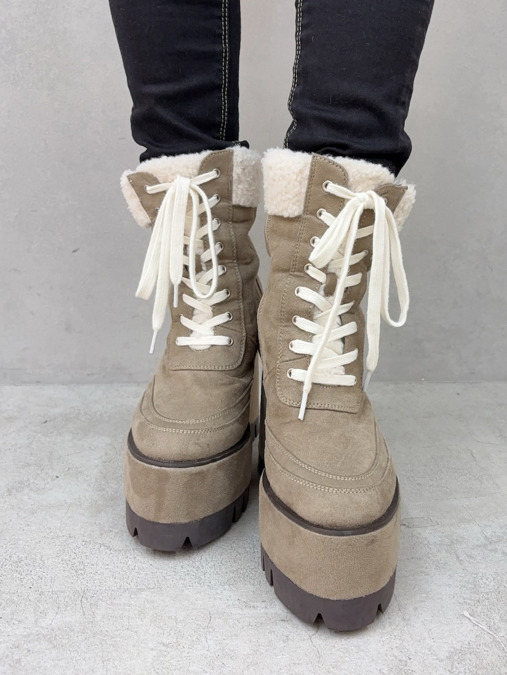 ブラック系のデニムパンツ、ベージュ系のブーツ、ホワイト系のニット/セーターを着用したレディースの秋コーディネートの5枚目の写真