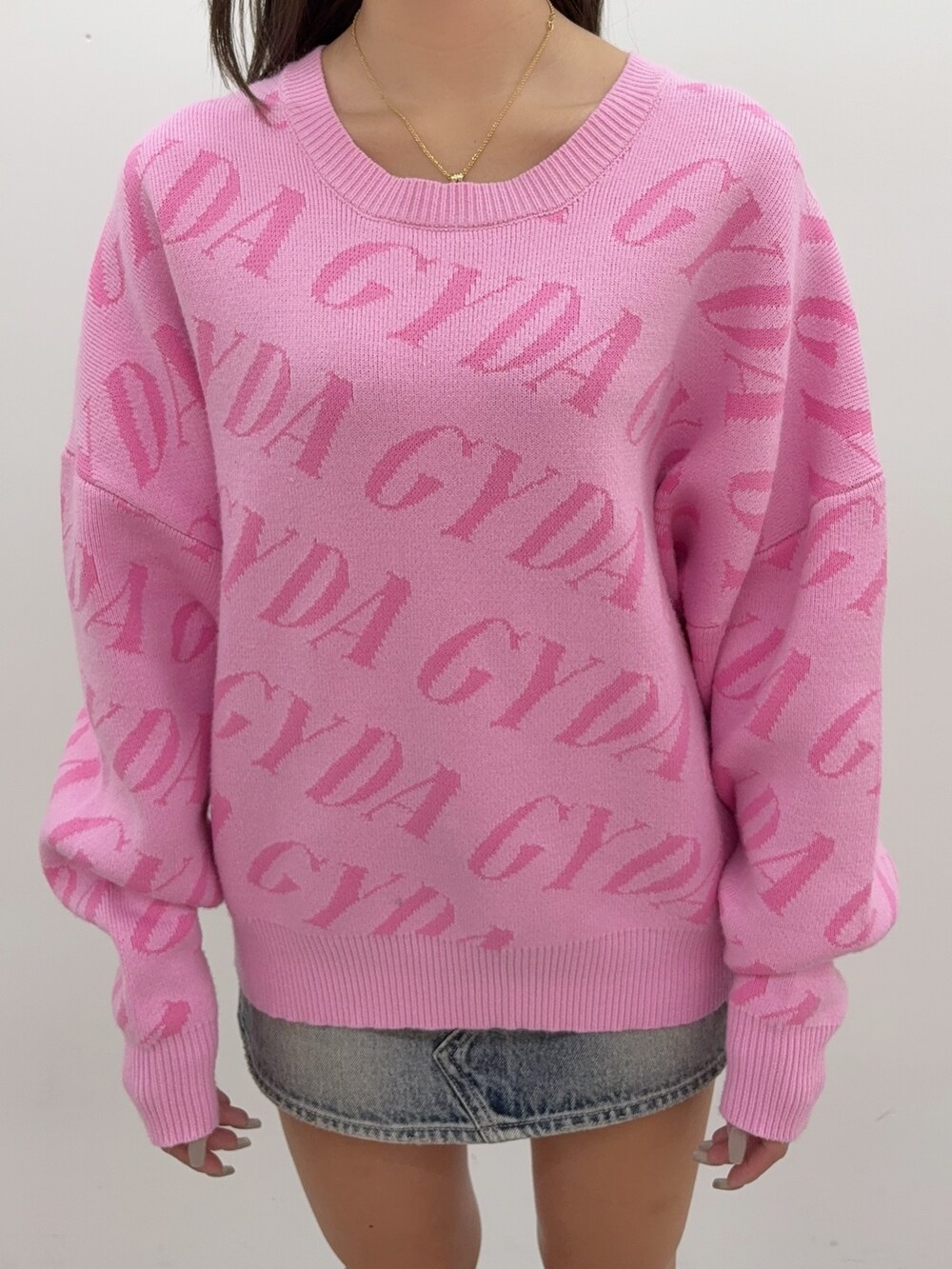 ピンク系のニット/セーター、ブルー系のデニムスカート、ブラック系のブーツを着用したレディースの秋コーディネートの4枚目の写真