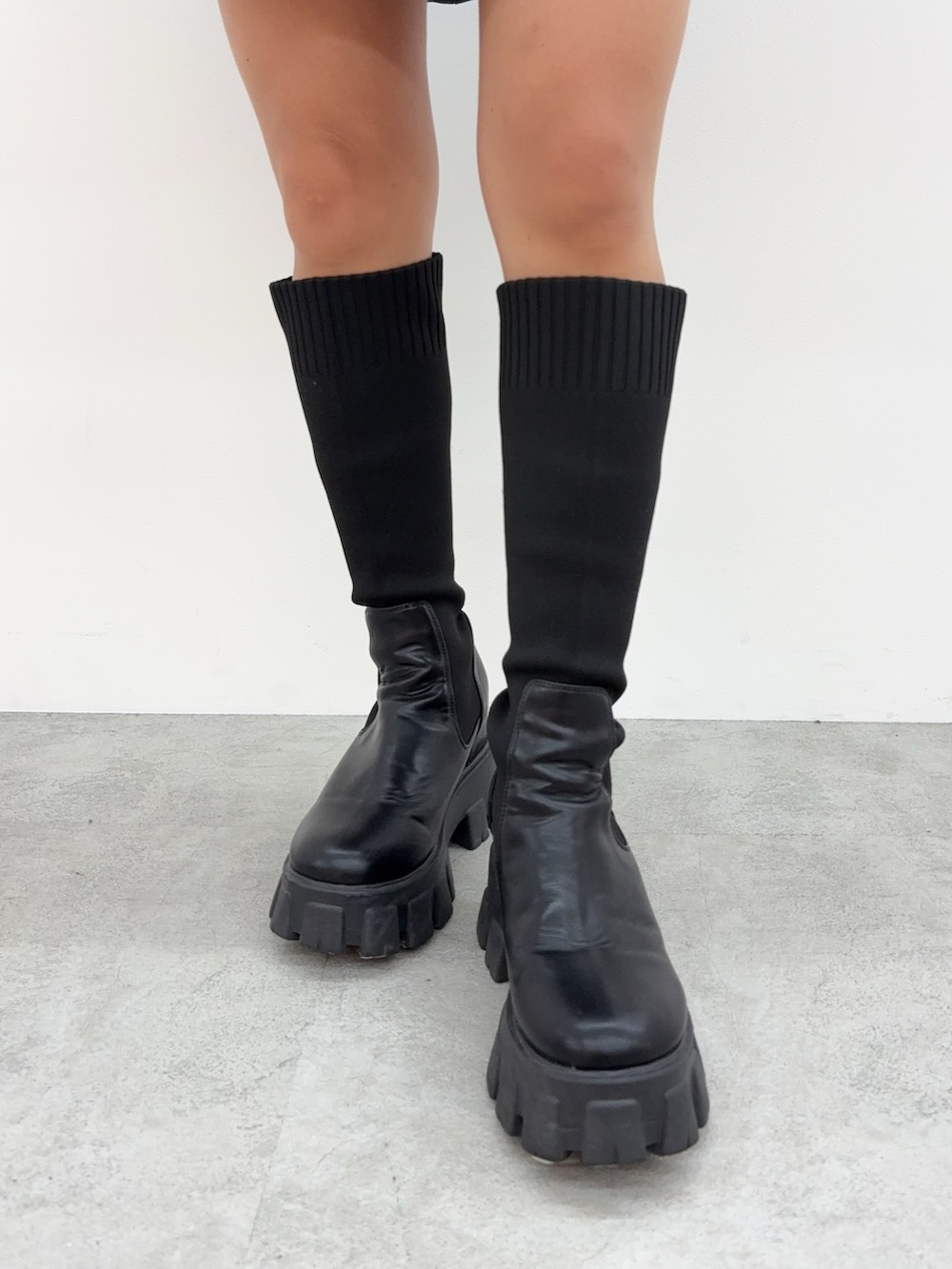 ホワイト系のスウェット、ブルー系のデニムスカート、ブラック系のブーツを着用したレディースの秋コーディネートの5枚目の写真