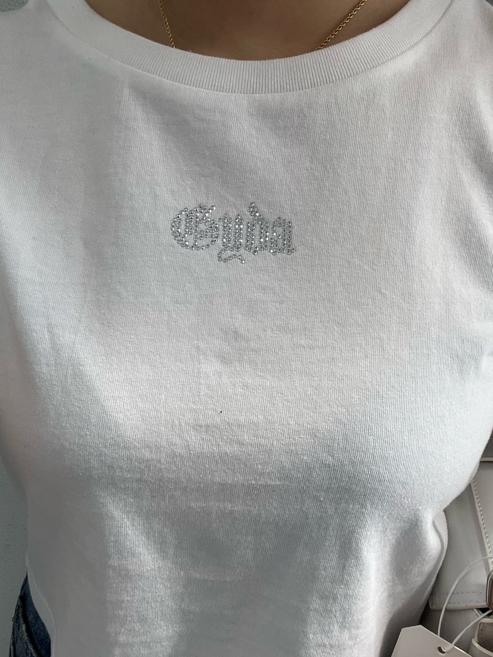 ホワイト系のTシャツ/カットソー、ホワイト系のハンドバッグ、ブルー系のデニムパンツを着用したレディースの春コーディネートの4枚目の写真