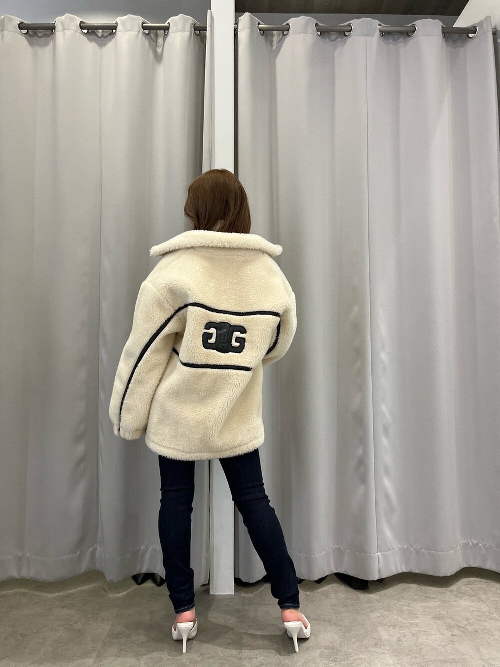 ホワイト系のブルゾン、ホワイト系のニット/セーター、ブルー系のつなぎ/オールインワンを着用したレディースの冬コーディネートの3枚目の写真