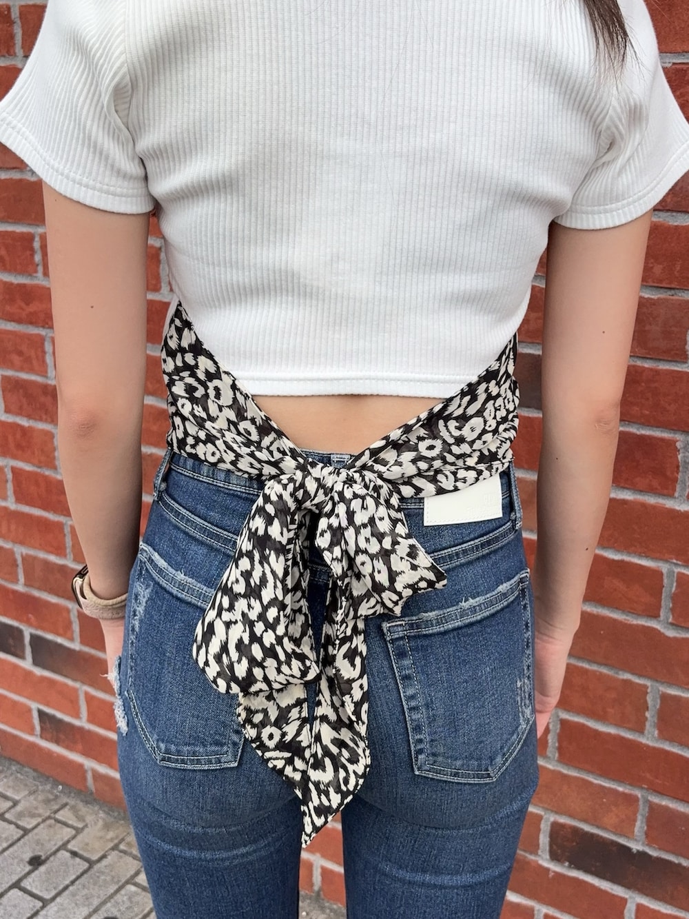 ホワイト系のTシャツ/カットソー、ブルー系のデニムパンツ、ホワイト系のサンダルを着用したレディースの夏コーディネートの4枚目の写真