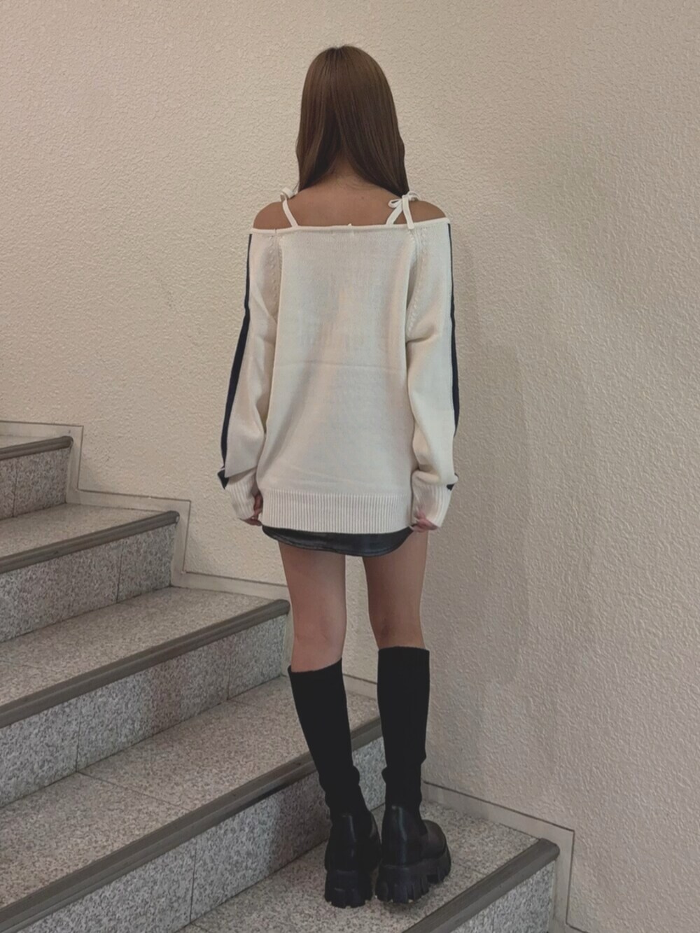 ブラック系のブーツ、ブラック系のスカート、ホワイト系のニット/セーターを着用したレディースの秋コーディネートの3枚目の写真