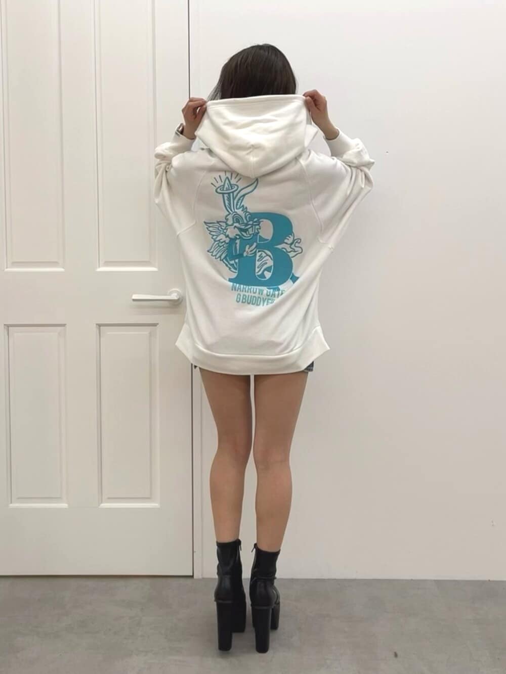 ブラック系のブーツ、ブルー系のデニムスカート、ホワイト系のパーカーを着用したレディースの冬コーディネートの3枚目の写真