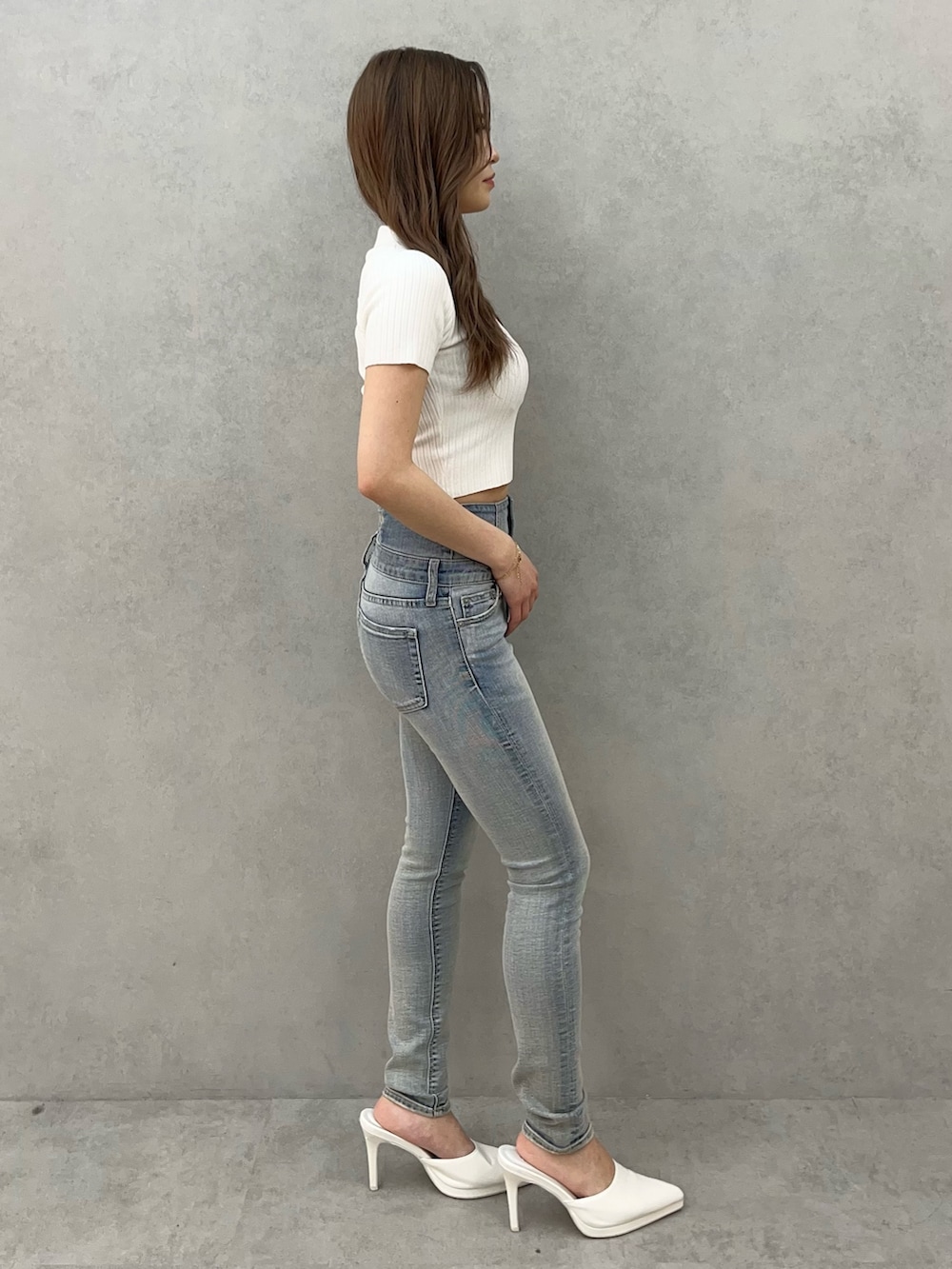 ホワイト系のニット/セーター、ブルー系のデニムパンツ、ホワイト系のパンプスを着用したレディースの春コーディネートの2枚目の写真