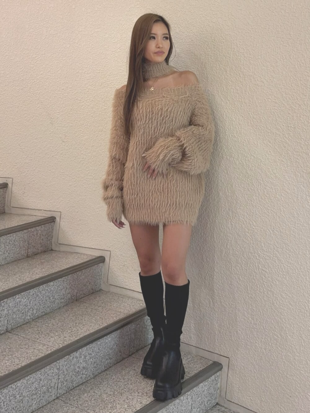 ブルー系のデニムスカート、ブラック系のブーツ、ベージュ系のニット/セーターを着用したレディースの秋コーディネートの2枚目の写真